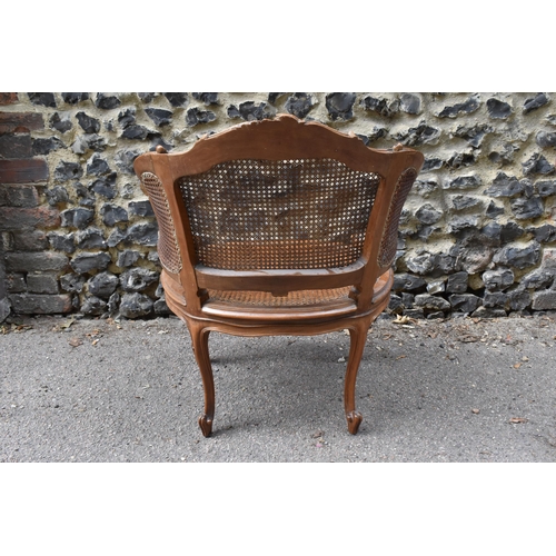 428 - A Louis XV style canned bergère armchair, with curved backrest, the carved back rail with central ro... 