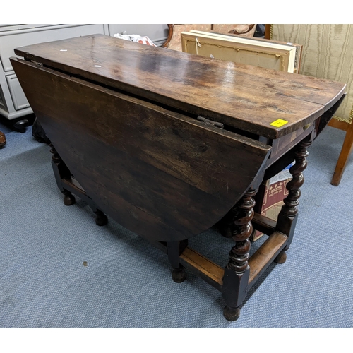 11 - An early 18th century gateleg table, possibly elm wood and having single drawer, two fall flaps and ... 