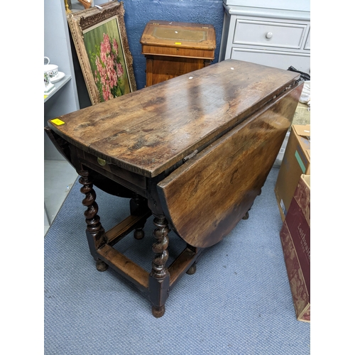 11 - An early 18th century gateleg table, possibly elm wood and having single drawer, two fall flaps and ... 