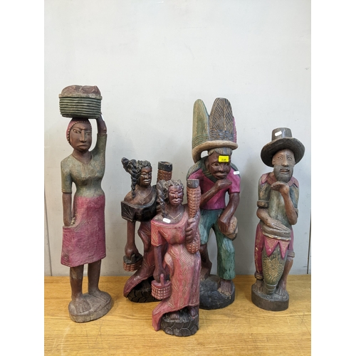 238 - A group of five African painted and carved wooden statues to include a bearded man with a drum, the ... 