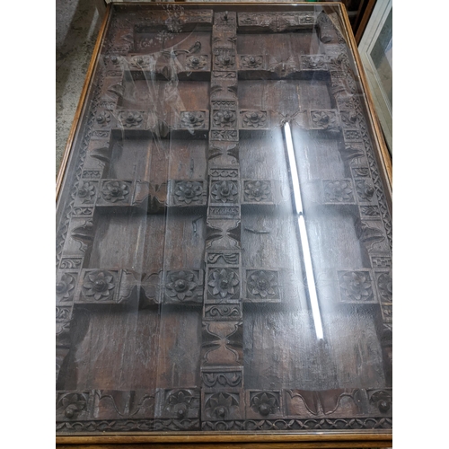 354 - A Large Asian carved wooden door panel coffee table, the carved door panel ornately worked, with wro... 