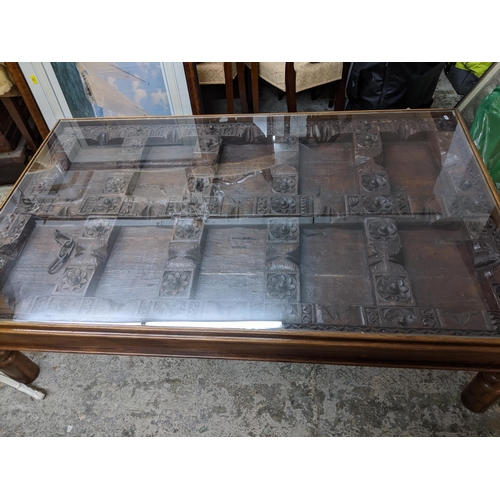 354 - A Large Asian carved wooden door panel coffee table, the carved door panel ornately worked, with wro... 