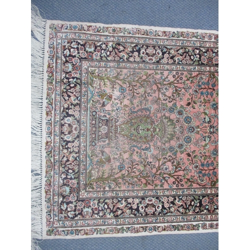 7 - A Persian silk hand woven rug having a pink ground decorated with birds amongst a floral design and ... 