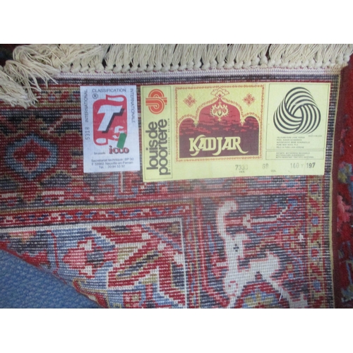 23 - A machine woven Kadjar rug having a red ground, central motif and tasselled ends 140cm x 197cm Locat... 