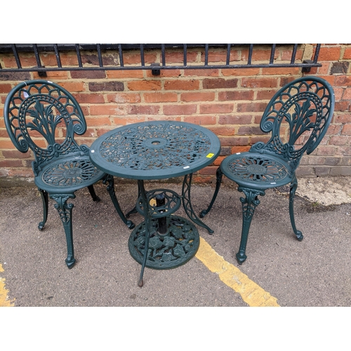 303 - A green painted cast aluminium garden two-tier table with parasol base, and two garden chairs Locati... 