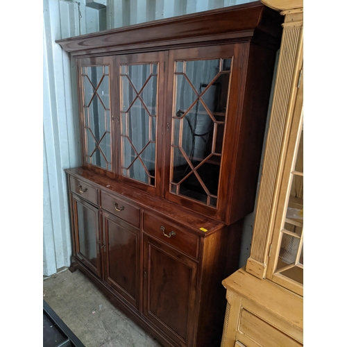 486 - A reproduction mahogany bookcase having three astragal glazed doors above drawers and cupboard doors... 