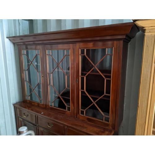 486 - A reproduction mahogany bookcase having three astragal glazed doors above drawers and cupboard doors... 