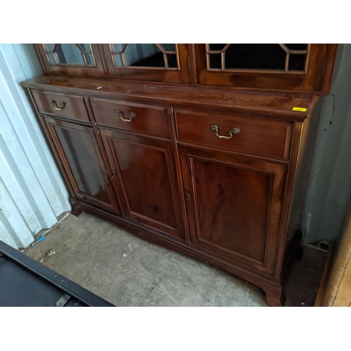 486 - A reproduction mahogany bookcase having three astragal glazed doors above drawers and cupboard doors... 