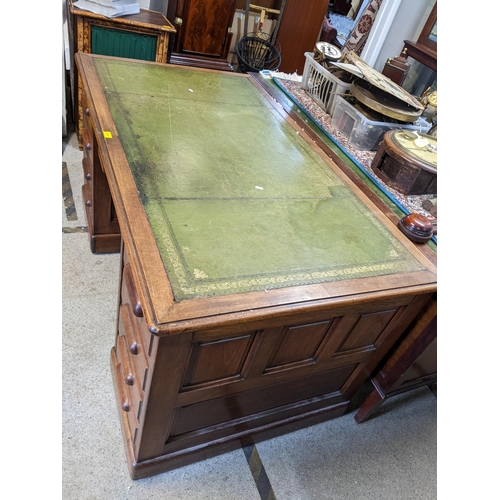 511 - A 1940's twin pedestal writing desk having a green leather topped scriber, nine drawers and on a pli... 