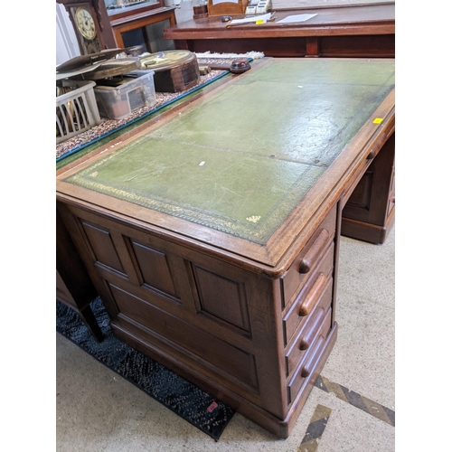 511 - A 1940's twin pedestal writing desk having a green leather topped scriber, nine drawers and on a pli... 