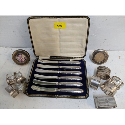 533 - A group of nine silver napkin rings, two small silver photograph strut frames, and a cased set of si... 