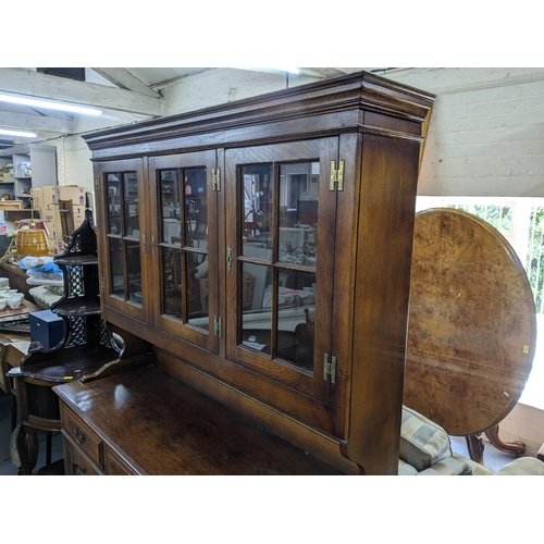 541 - A reproduction oak dresser having three glazed doors above three drawers and three cupboard doors 18... 