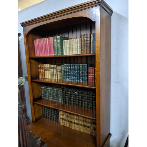 555 - A good quality oak bookcase, shaped cornice with arched apron four open shelves, above a base with t... 