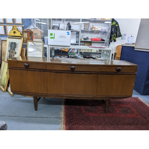 85 - An Elliots of Newbury bow fronted teak sideboard with three drawers over three cupboards on tapered ... 