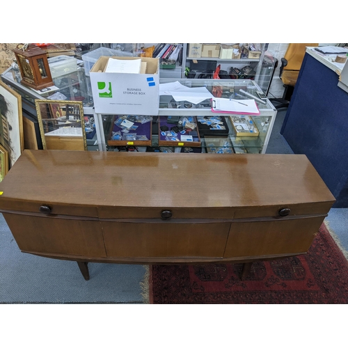 85 - An Elliots of Newbury bow fronted teak sideboard with three drawers over three cupboards on tapered ... 