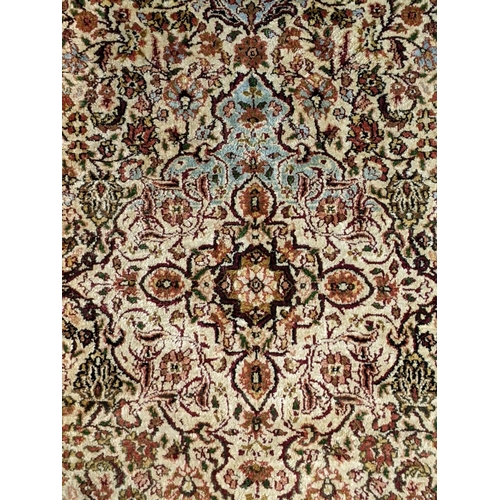 66 - A handwoven Indian design rug with a central motif and decorated with flowers and foliage on a cream... 