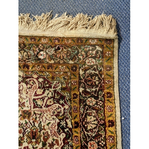 66 - A handwoven Indian design rug with a central motif and decorated with flowers and foliage on a cream... 