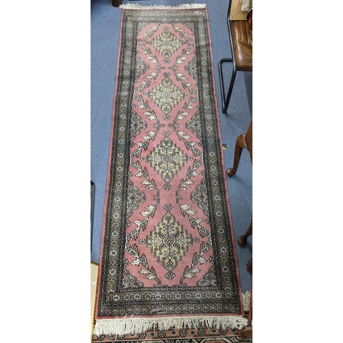 70 - A handwoven Turkish runner with four repeating motifs decorated with foliage on a mottled pink backg... 