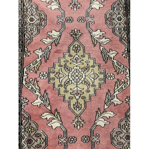 70 - A handwoven Turkish runner with four repeating motifs decorated with foliage on a mottled pink backg... 