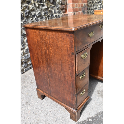 135 - An early George III walnut and feather-banded kneehole desk, the bookmatched veneer top with herring... 