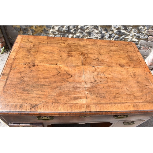 135 - An early George III walnut and feather-banded kneehole desk, the bookmatched veneer top with herring... 