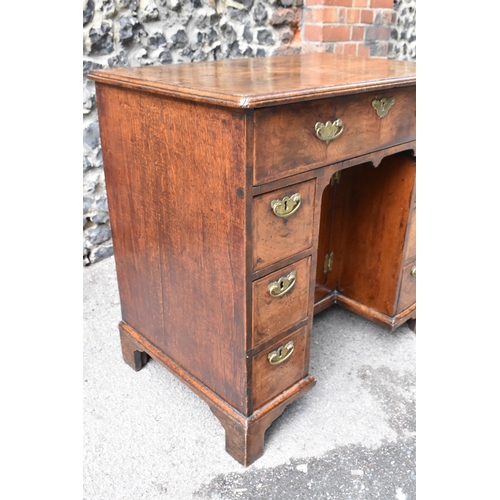 135 - An early George III walnut and feather-banded kneehole desk, the bookmatched veneer top with herring... 