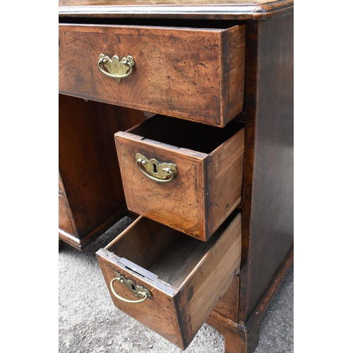 135 - An early George III walnut and feather-banded kneehole desk, the bookmatched veneer top with herring... 