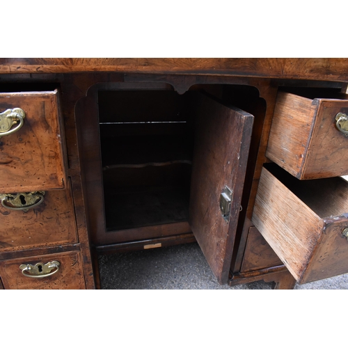 135 - An early George III walnut and feather-banded kneehole desk, the bookmatched veneer top with herring... 