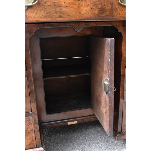 135 - An early George III walnut and feather-banded kneehole desk, the bookmatched veneer top with herring... 