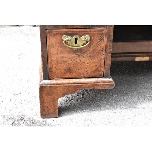 135 - An early George III walnut and feather-banded kneehole desk, the bookmatched veneer top with herring... 