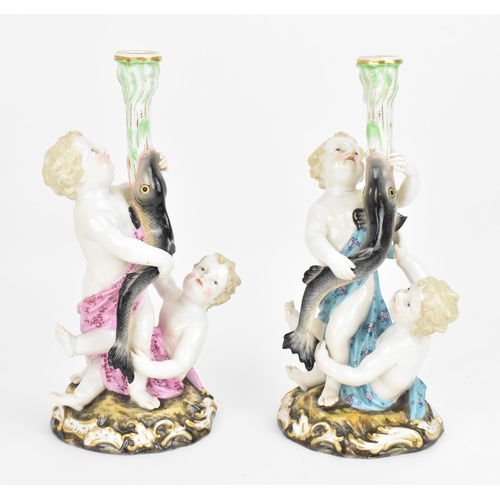 152 - Two Meissen figural candlesticks, 19th century, each modelled as two putti supporting a fish issuing... 