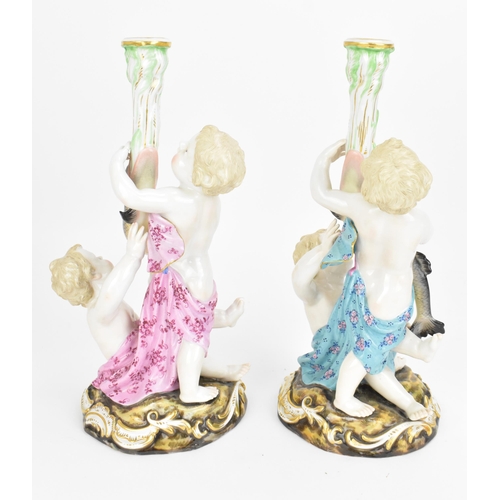 152 - Two Meissen figural candlesticks, 19th century, each modelled as two putti supporting a fish issuing... 