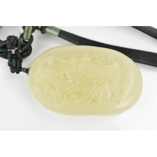 32 - A Chinese carved celadon jade pendant, late Qing dynasty/early 20th century, of oval form with front... 