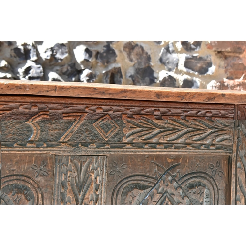 149 - A late 17th century oak coffer, with four carved panel top and foliate carved four panel front on st... 