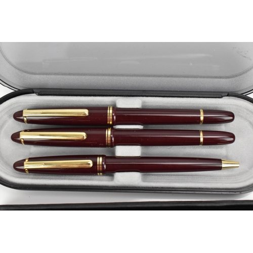 84 - A cased set of pens, comprising two fountain and one ballpoint pen, each with maroon barrel and gilt... 