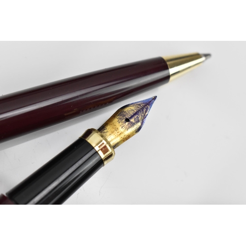 84 - A cased set of pens, comprising two fountain and one ballpoint pen, each with maroon barrel and gilt... 