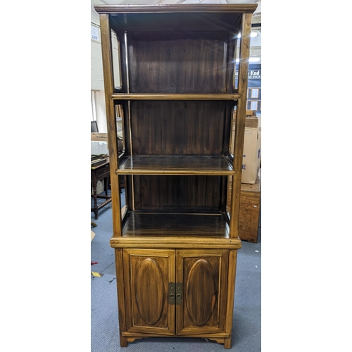 401 - A Chinese stained elm cabinet having a moulded cornice, three open shelves and two cupboard doors be... 