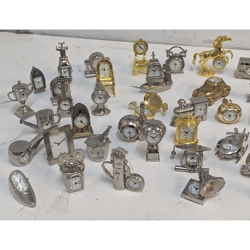 121 - A collection of approx 70 miniature novelty quartz clocks in various forms to include Ship, Car, Pip... 