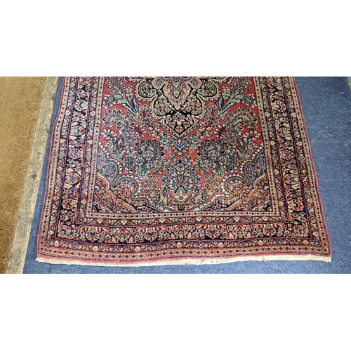 10 - A Persian hand woven, red ground rug having a central motifs, floral design and multiguard borders, ... 