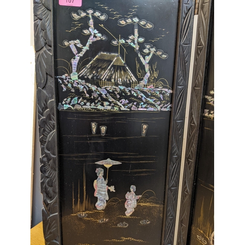 107 - An early 20th century Japanese black ebonized four fold wood and inlaid screen, four panels with fig... 