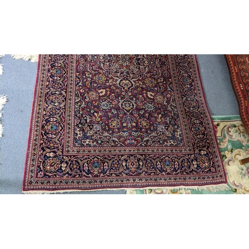 5 - A Persian hand woven Sarouk rug having a red ground and scrolling vines, surrounding a central motif... 