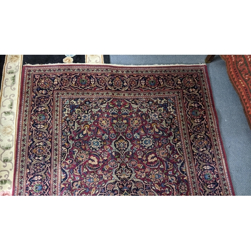 5 - A Persian hand woven Sarouk rug having a red ground and scrolling vines, surrounding a central motif... 