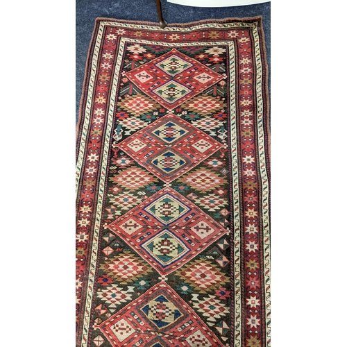 6 - A Kurdish hand woven runner having seven diamond motifs on a red ground, 327 x 96, Location: LWM