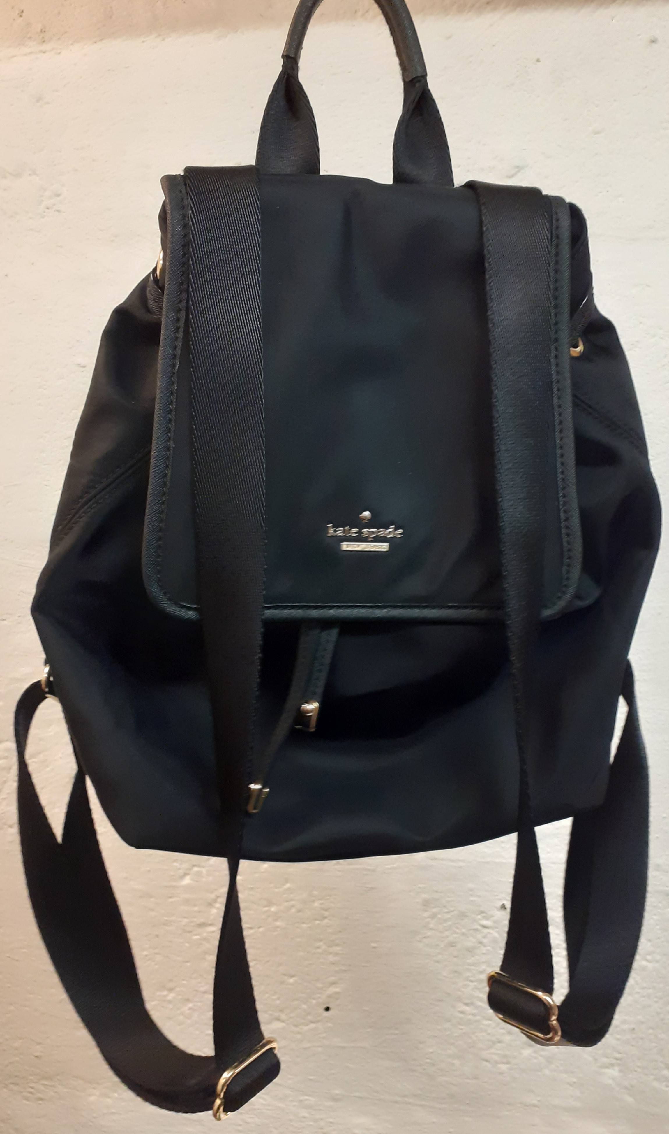 Kate Spade A black nylon waterproof backpack with drawstring closure having a fold over flap to the