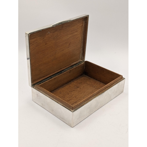 280 - A white metal cigarette box having wooden interior and marks to base, together with fitted presentat... 