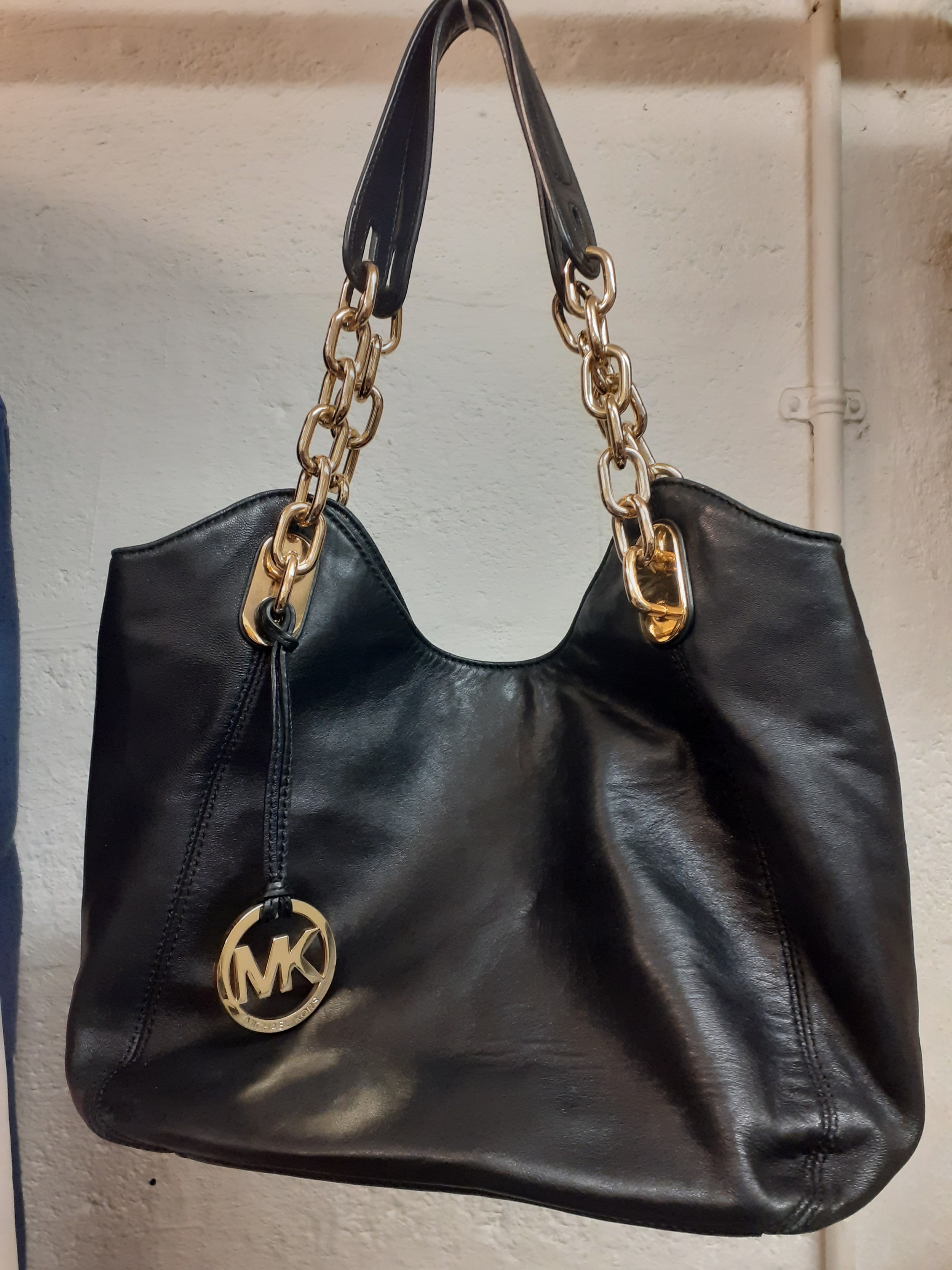 Michael Kors A modern black soft leather shoulder bag having gold tone chain partial straps and a br