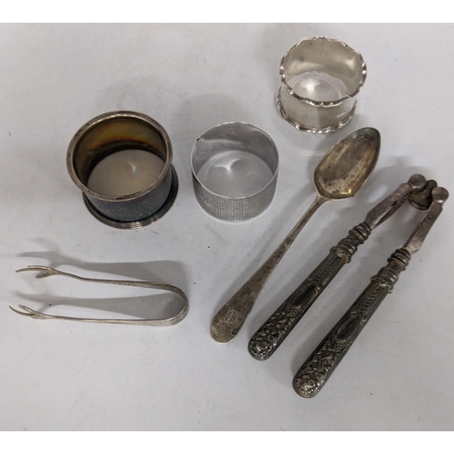 101 - Six pieces of silver to include a spoon, sugar tongs, a pair of nutcrackers and three napkin rings, ... 