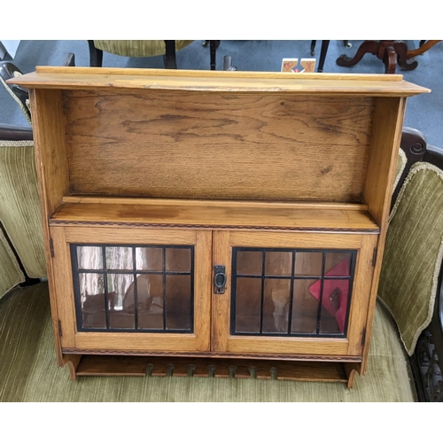 115 - An early 20th century light oak wall hanging display cabinet having two glazed doors and hanging rac... 