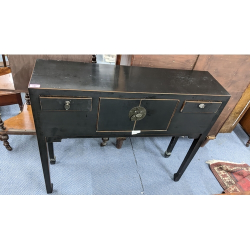 187 - An Oriental black lacquered console table having drawers flanking two cupboard doors, 81.5cm h x 96c... 