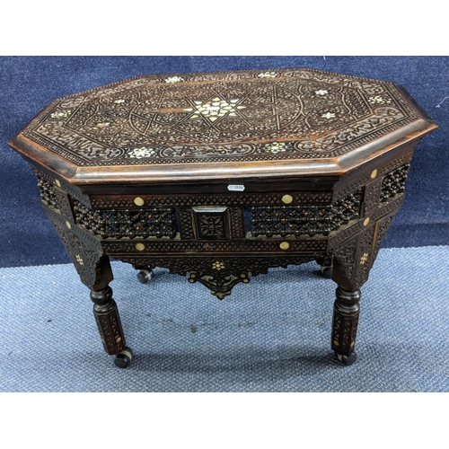 207 - A late 19th/early 20th century Middle Eastern heavily carved occasional table having mother of pearl... 